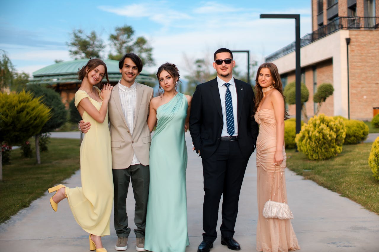 Group of young adults posing in stylish formal wear outdoors, exuding elegance and sophistication.